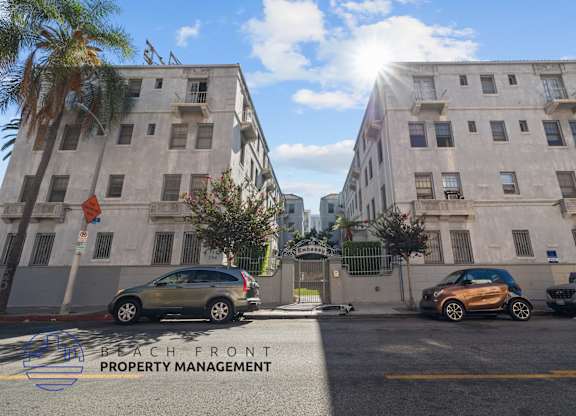 a city street with cars parked in front of two tall buildings