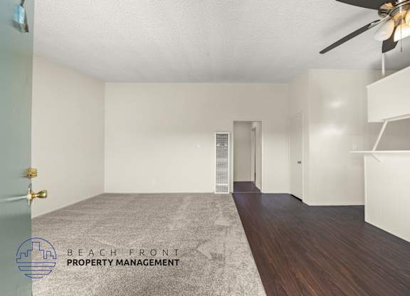 A spacious room with a ceiling fan and a rug on the floor.