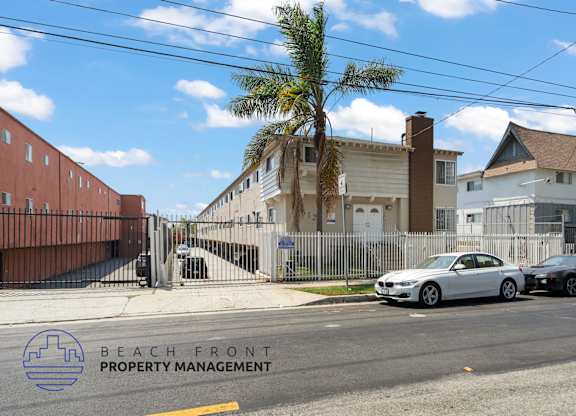 A street view with cars parked on the side and a building with the text