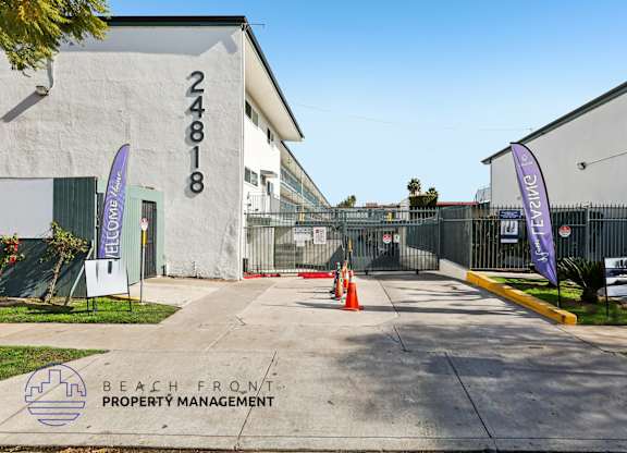 The image shows a building with the number 24818 on it, surrounded by a fence and a couple of flags.