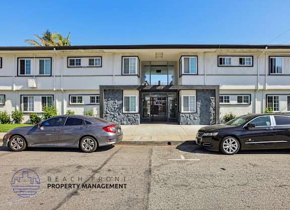 Two cars are parked in front of a building with the logo