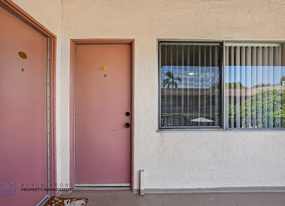 A pink door and window with a view of trees outside.