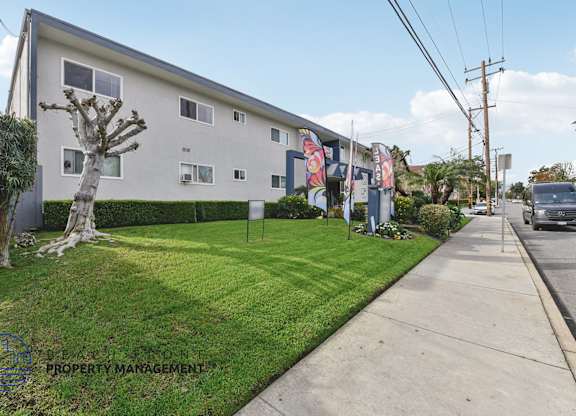 A white two-story building with a green lawn in front.