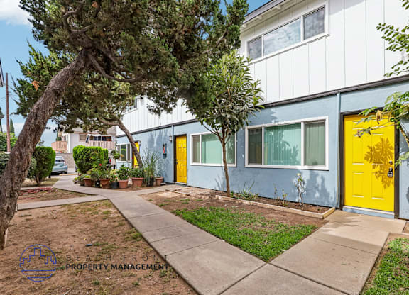 A building with a yellow door is surrounded by greenery.