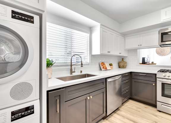 A modern kitchen with a washing machine on the left and a stove on the right.