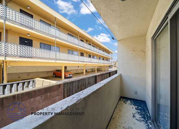 A balcony of a building with a car parked on the street below.