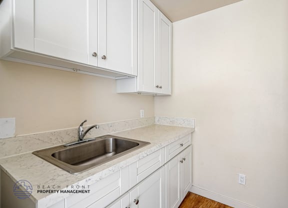 A kitchen with white cabinets and a marble countertop.