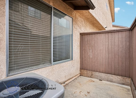 A concrete patio with a fan and a wooden fence.