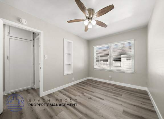 A room with a ceiling fan and a window with blinds.