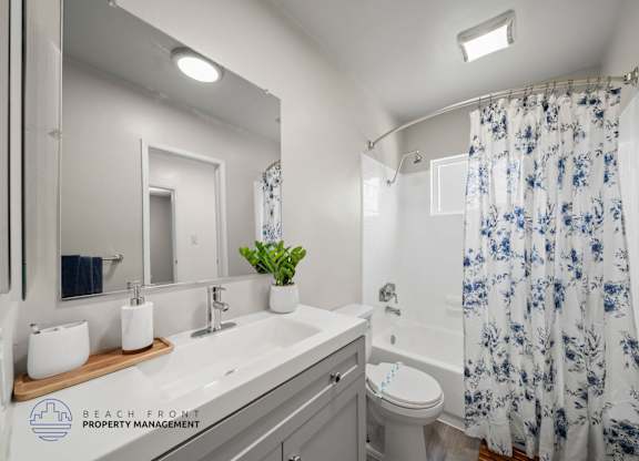 A bathroom with a white sink, toilet, and shower curtain.