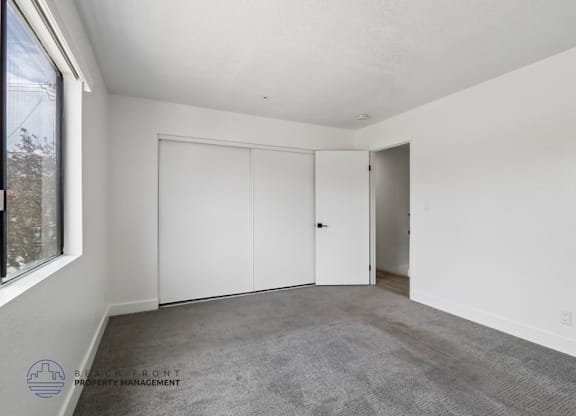 A room with white walls and a grey carpet.