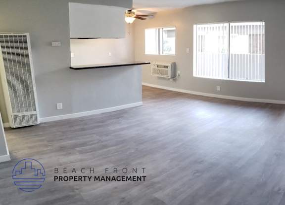 A spacious room with a ceiling fan and sliding glass doors leading to a balcony.