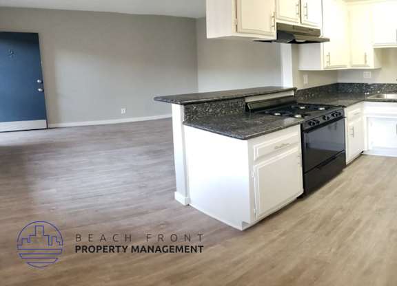 A kitchen with a black countertop and white cabinets.