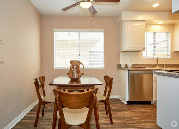 a dining area with a table and chairs and a kitchen in the background