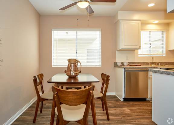 a dining area with a table and chairs and a kitchen in the background