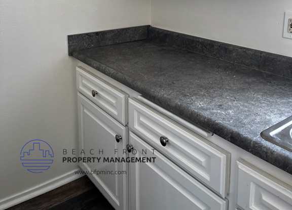 a kitchen with white cabinets and gray countertops