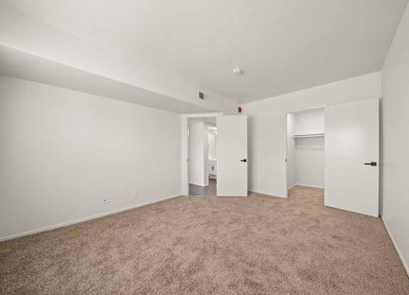 A large, empty room with carpeted flooring and white walls.