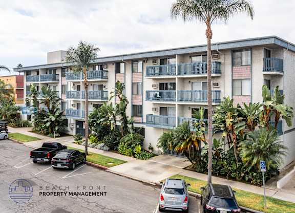 A building with balconies and palm trees in front.