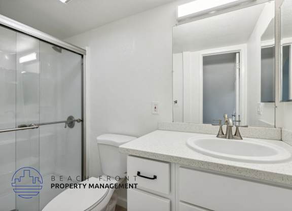 A bathroom with a sink, mirror, and shower.