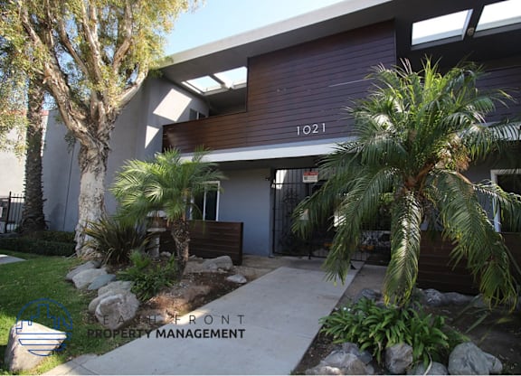 A building with the number 1021 on it is surrounded by plants and trees.