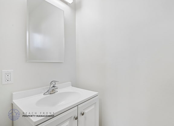 A white sink in a bathroom with a mirror above it.