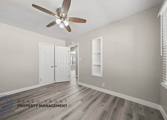 A room with a ceiling fan and a logo for Beach Front Property Management.