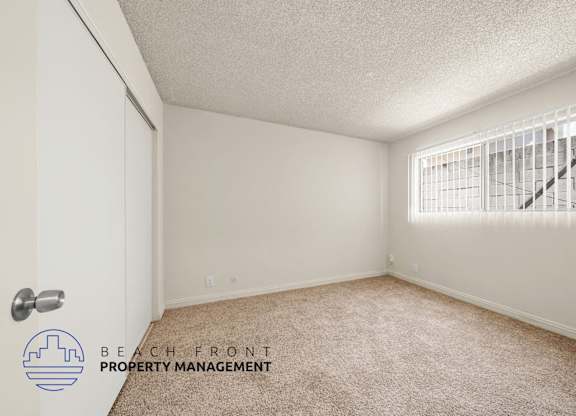 A room with a carpeted floor and a window with blinds.