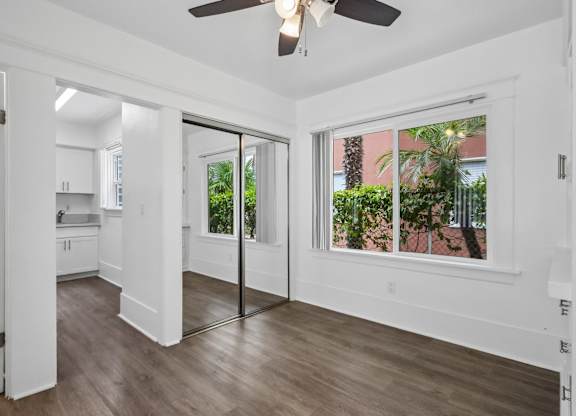 A room with a ceiling fan and sliding glass doors.