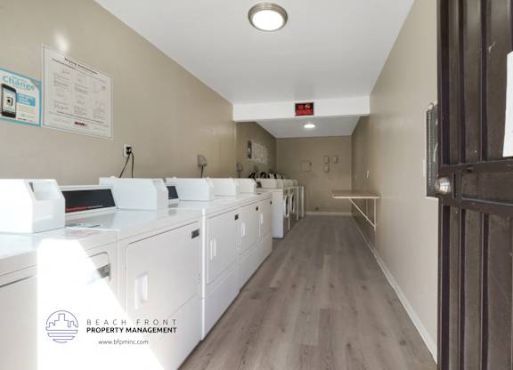 A laundry room with washers and dryers and a sign that says Beach Front Property Management.