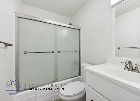 A white bathroom with a toilet, sink, and shower.