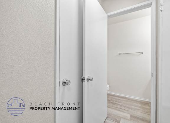 A white door with a handle and a logo of Beach Front Property Management on the bottom left.
