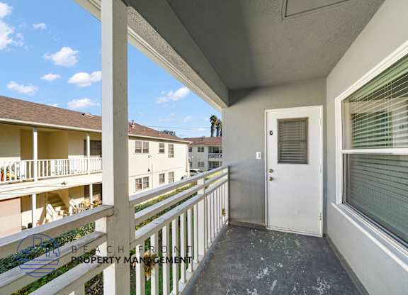 A balcony with a white door and window with blinds.