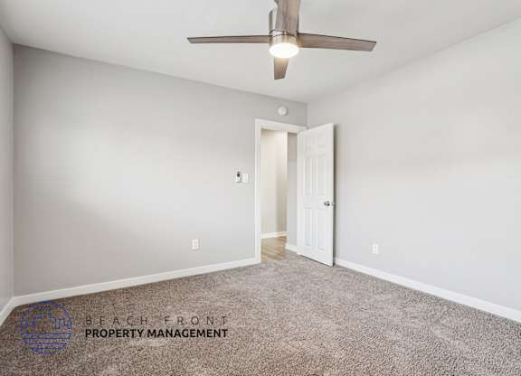 A room with a carpeted floor and a ceiling fan.