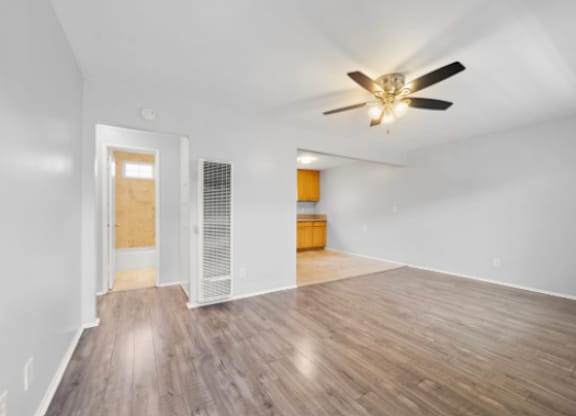 A room with a ceiling fan and wooden flooring.