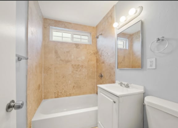 A bathroom with a white tub, sink, and toilet.