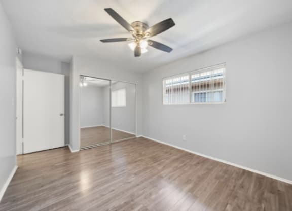 A room with a ceiling fan and wooden flooring.