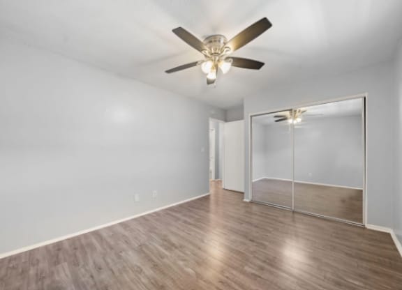 A room with a ceiling fan and a mirror on the wall.