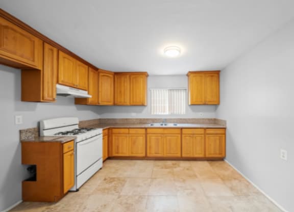 A kitchen with wooden cabinets and a white stove top oven.