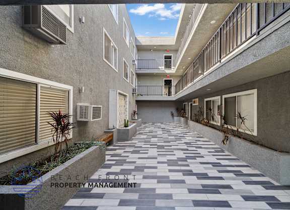 A long, narrow walkway with alternating black and white tiles leads to a balcony.