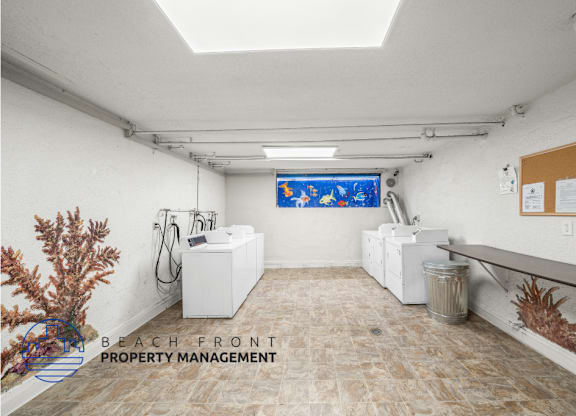 view of onsite laundry room with  three washing and drying machines and a fish mural
