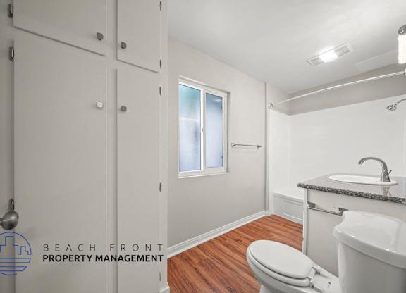 A bathroom with a toilet, sink, and a window.