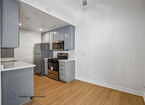 A kitchen with a white counter top and wooden floors.