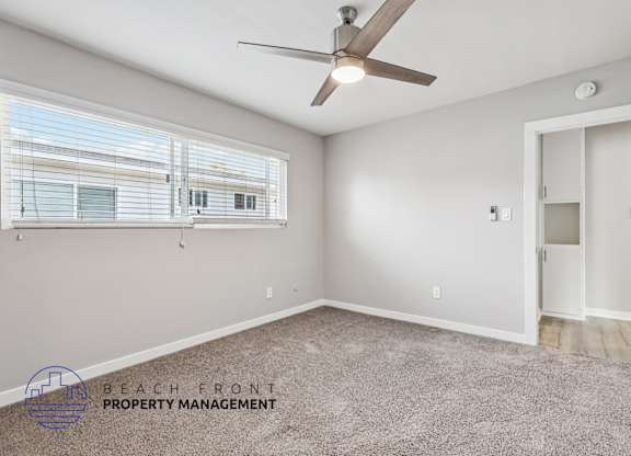 A room with a ceiling fan and a window with blinds.