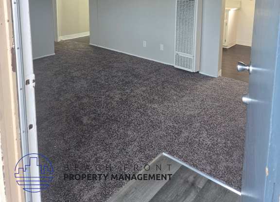 A room with a carpeted floor and a door on the right side.