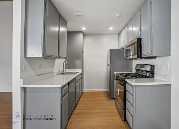 A kitchen with stainless steel appliances and wooden floors.