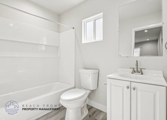 A white bathroom with a toilet, sink, and mirror.