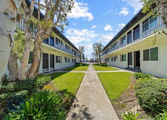 a courtyard between two units of a building with grass and trees