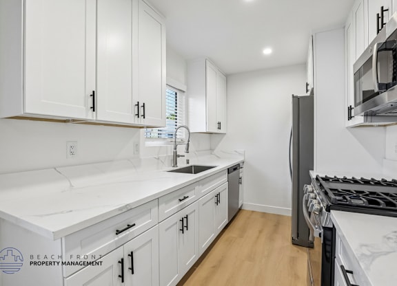 A kitchen with white cabinets and a black stove top.