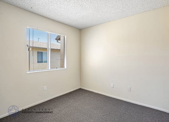 A room with a window and a carpeted floor.