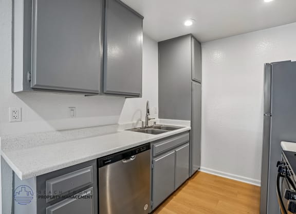 A kitchen with a stainless steel dishwasher and refrigerator.